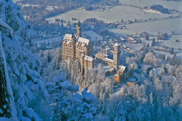 a view of a snow covered mountain with Neuschwanstein Castle in the background