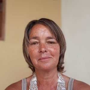 Person with short hair wearing a gray tank top, smiling slightly.