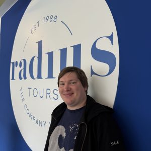 Person smiling, standing against a blue wall with 'radius tours' logo.