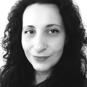 Black and white portrait of a person with curly hair smiling slightly.